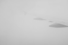 Airplane wing, barely visible through the clouds.