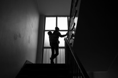 Silhouetted woman carrying her child in a stairwell