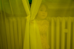 Lumi hiding behind a yellow curtain