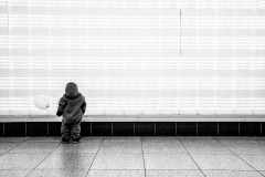 Lumi, balloon in hand, standing before and looking up a wall of lights