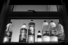 Plastic bottles of drinking water in a window, light by the sun from behind