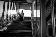 A woman walking down the stairs to the train platform