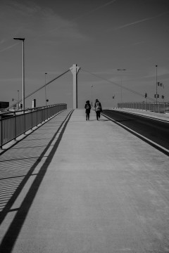 Two people walking up a bridge
