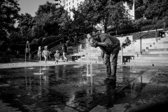 A man is cooling his head in a public fountain