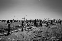 People at the Templehof Park watch a large number of kites in the sky