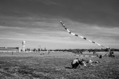 People sitting on the gras, watching a huge kite above them