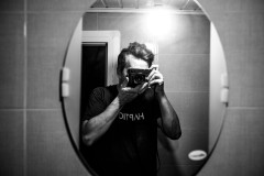 Me, photographing myself through a mirror with a bare light bulb illuminating the room