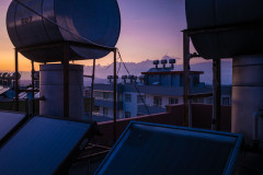 Rooftop filled with solar hear units, purple, sunset sky in the background