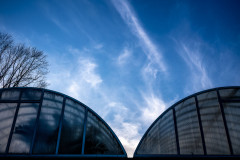 Silhouetted greenhouses below a blue sky with some clouds