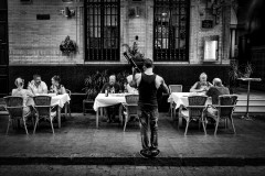 A guitarist is playing for people seated at a restaurant in the streets of Seville