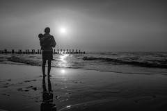Mother and child looking into the sunset at the beach