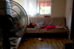 Fan in the foreground, mother and child taking a nap in the out of focus background