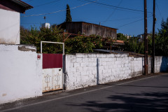 Street in Erzin, white wall with a red door