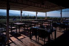 Outside veranda, with lots of tables set up waiting for the first guests to arrive, with a nice view on Dörtyol and the mountains behind it all
