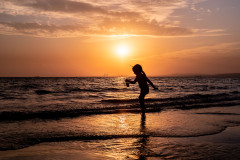 My daughter, silhouetted, playing in the ocean, with a beautiful sunset as the backdrop