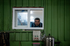 A worker looking at the camera through a window of the olive oil factory