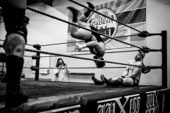 A wrestler canon-balling into the corner on top of his opponent