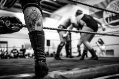 Tattoo on the leg of a wrestler, with action going on inside the ring behind