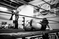 A beaten Hős Antal lies in the ring, while Yuval Goldshmit is celebrating his victory at wXw Wrestling Academy's LIVE Vol. 3 event