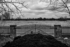 A field behind a fence  behind a pile of earth