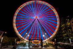 Ferris wheel in blurred motion, covered in red and blue light during night time