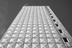 Monochome image of a highrise building with no windows, shot from close by and below