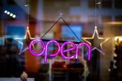 An pink, neon open sign hangs in a shop window