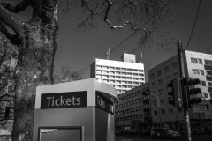 Monochrome image of the A41 highrise, which is in the background. The foreground comprises of a ticket machine, a traffic light and a tree.