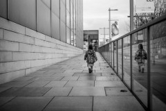 My daughter walking alway from the camera, along Folkwang Museum, her reflection seen in the glass railing on the right