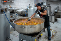 A volunteer steers food in a massive pot inside the Gönül Mutfağı (tr. 