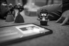 Lego Mario sitting on the carpet next to an iPad showing a software update in progress on his chest screen