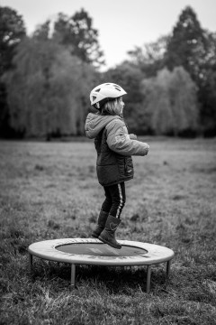My daughter jumping on a small trampoling in the middle of a meadow.