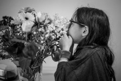 Monochrome image of my daughter putting her nose right up to a bouquet of flowers
